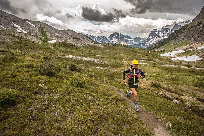 A woman running through mountainous alpine terrain