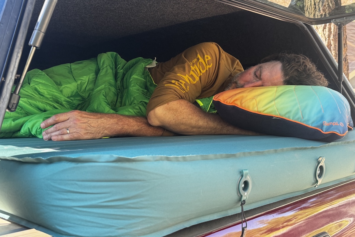 A man sleeping on the Exped MegaMat Duo set up in a truck bed