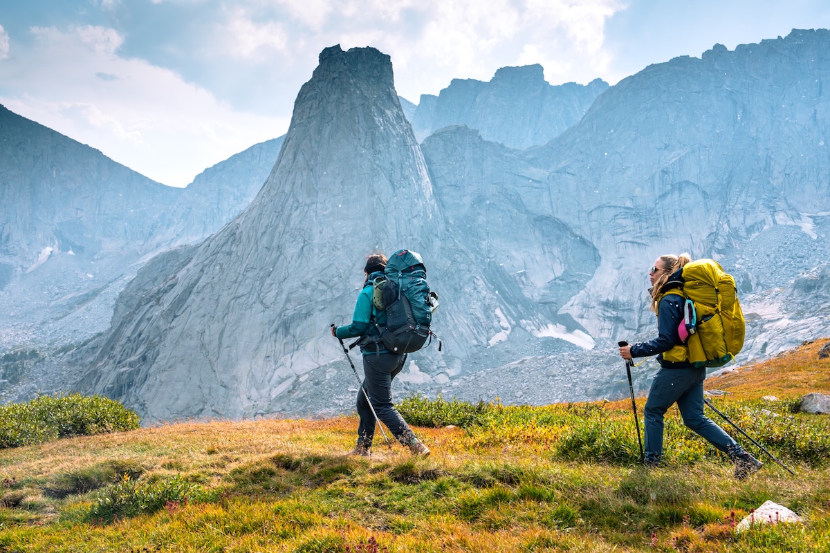 Two women walk along a trail with the Cirque of the Towers in Wyoming in the background