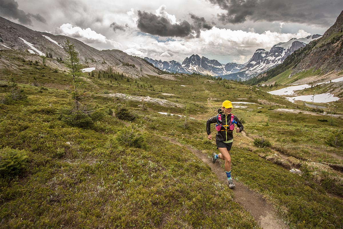 A woman running through mountainous alpine terrain