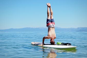 A man performing a head stand on the Dax DownDog stand up paddle board on Lake Tahoe
