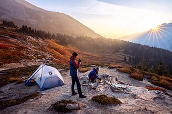 A Nemo tent set up at camp with the sun setting on the horizon