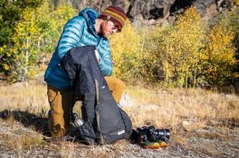 A backpacker takes time to packs his backpack before a long trip. 